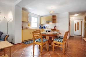 A kitchen with wooden cabinets, a dining table with chairs, and a visible window.