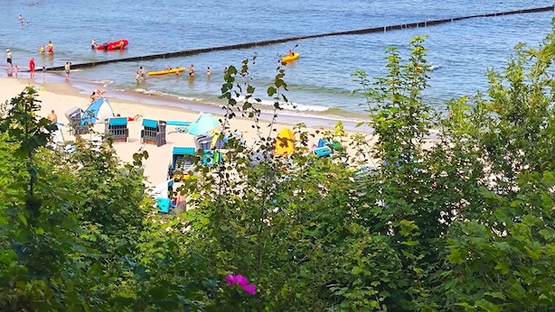 Eine Steg, der sich ins Wasser erstreckt, mit einem Strand im Vordergrund.