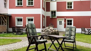 Ein Innenhof mit Sitzgelegenheiten im Freien, einer Steinsäule und einem Gebäude mit roten und weißen Außenwänden.