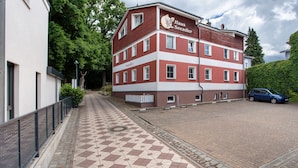 Ein mehrstöckiges Gebäude mit roter und weißer Fassade, einem gefliesten Gehweg und einem geparkten Auto.