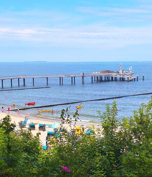 Eine Steg, der sich ins Wasser erstreckt, mit einem Strand im Vordergrund.