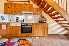 Une cuisine avec des meubles en bois, un four en acier inoxydable, une machine à café et un tapis à motifs.