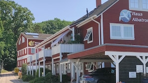 A row of red buildings with balconies, solar panels, and a sign reading 'Haus Albatros.'