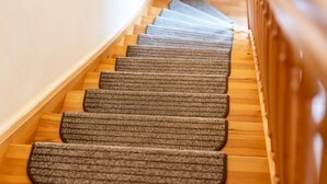 A carpeted staircase with wooden steps and a handrail.