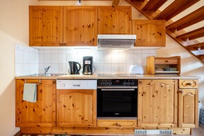 Una cucina con mobili in legno, lavastoviglie, fornello e forno a microonde.