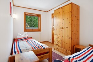 Une chambre à coucher avec un lit, une armoire en bois, une fenêtre et un radiateur.
