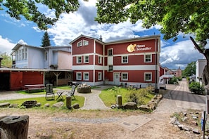 A red and white building with a sign reading 'Haus Seeadler.' There are outdoor seating areas, a stone pathway, and a small garden with rocks and plants. - Apartment "Haus Seeadler 8" with Shared Terrace & Wi-Fi (Koserow)