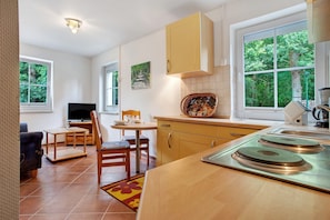 A compact kitchen with a dining area, a television, and a window with a view of trees. - Apartment "Haus Seeadler 8" with Shared Terrace & Wi-Fi (Koserow)