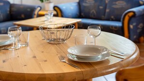 A dining table with plates, glasses, and cutlery, set in a room with a blue sofa and a wooden table. - Apartment "Haus Seeadler 9" with Shared Terrace & Wi-Fi (Koserow)