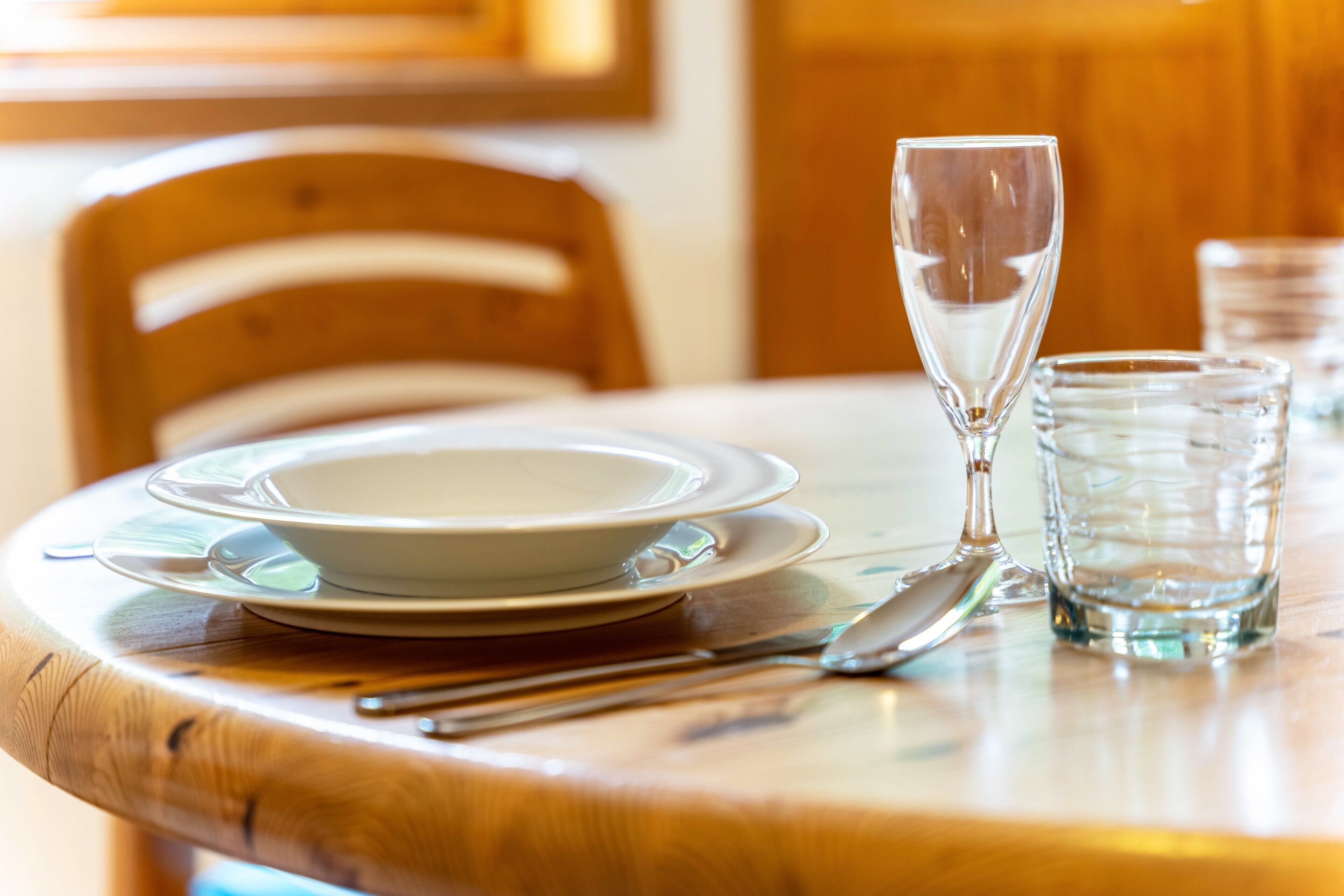 Uma mesa de jantar com um conjunto de pratos, uma taça de vinho e um copo de água.