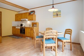 Una cocina con armarios de madera, una mesa de comedor con sillas y una lámpara colgante.