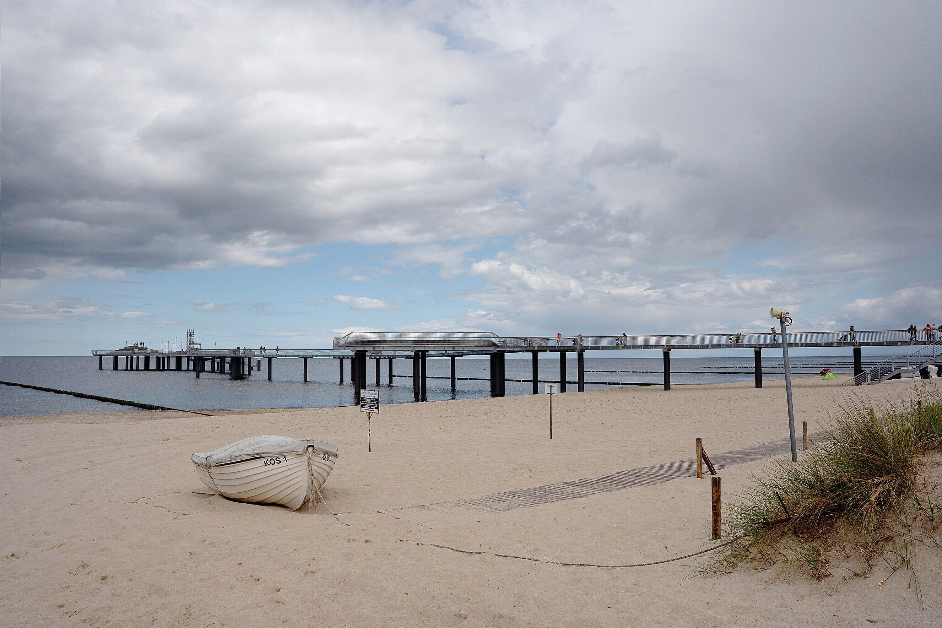 Ein Strand mit einem Boot, einem Steg und einem Schild.