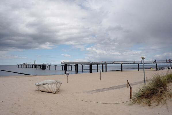 Une plage avec un bateau, une jetée et un panneau.