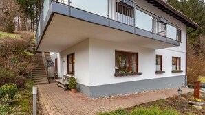 A two-story house with a balcony, a staircase, and a garden area. - Apartment 'Ferienwohnung Rehsiepen' with Mountain View, Private Terrace and Wi-Fi (Schmallenberg)