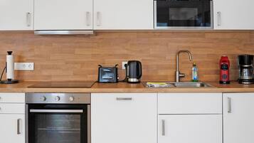 Una cocina moderna con armarios blancos, encimera de madera, horno empotrado, cafetera y tostadora.
