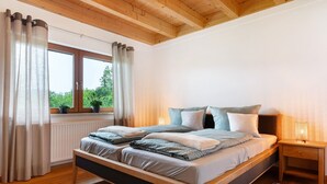 Un dormitorio con cama de madera, mesita de noche, ventana con cortinas y vistas al exterior.