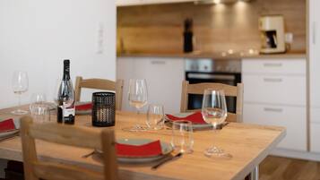 Uma mesa de jantar posta com copos de vinho, pratos e talheres, com uma garrafa de vinho e uma vela sobre a mesa.