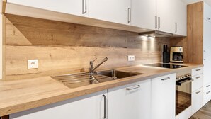 Una cocina moderna con encimera de madera, pileta de acero inoxidable y muebles de cocina blancos.