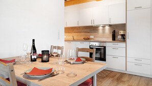Una cocina moderna con armarios blancos, encimera de madera y una mesa de comedor con copas de vino y platos.