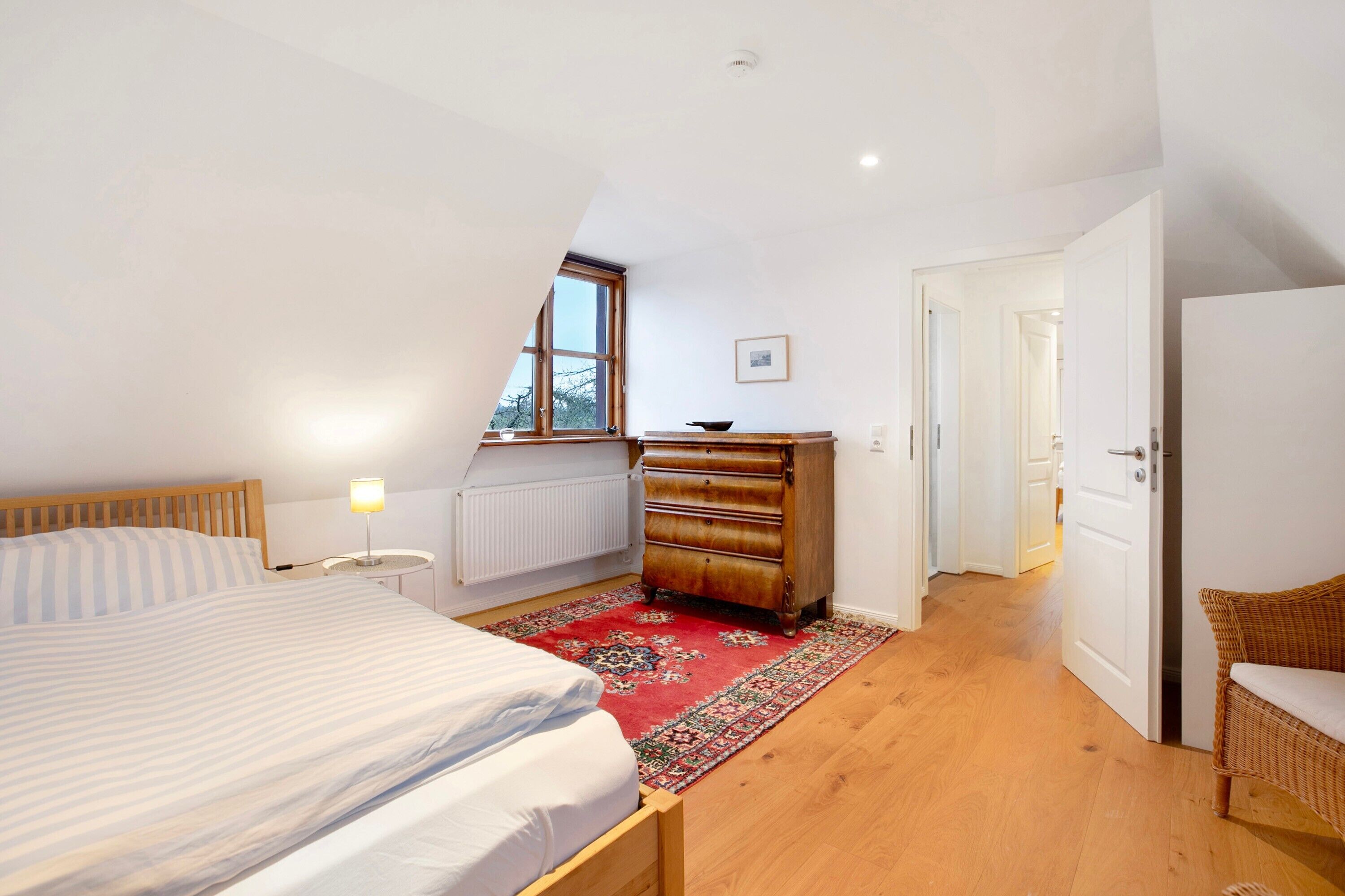 A bedroom with a bed, dresser, and a red rug.
