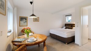Une chambre à coucher comprenant un lit, une table de chevet, une fenêtre et un coin repas avec une table et des chaises.
