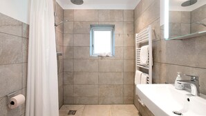 Une salle de bain moderne équipée d’une douche, d’une fenêtre, d’un lavabo et d’un porte-serviettes.