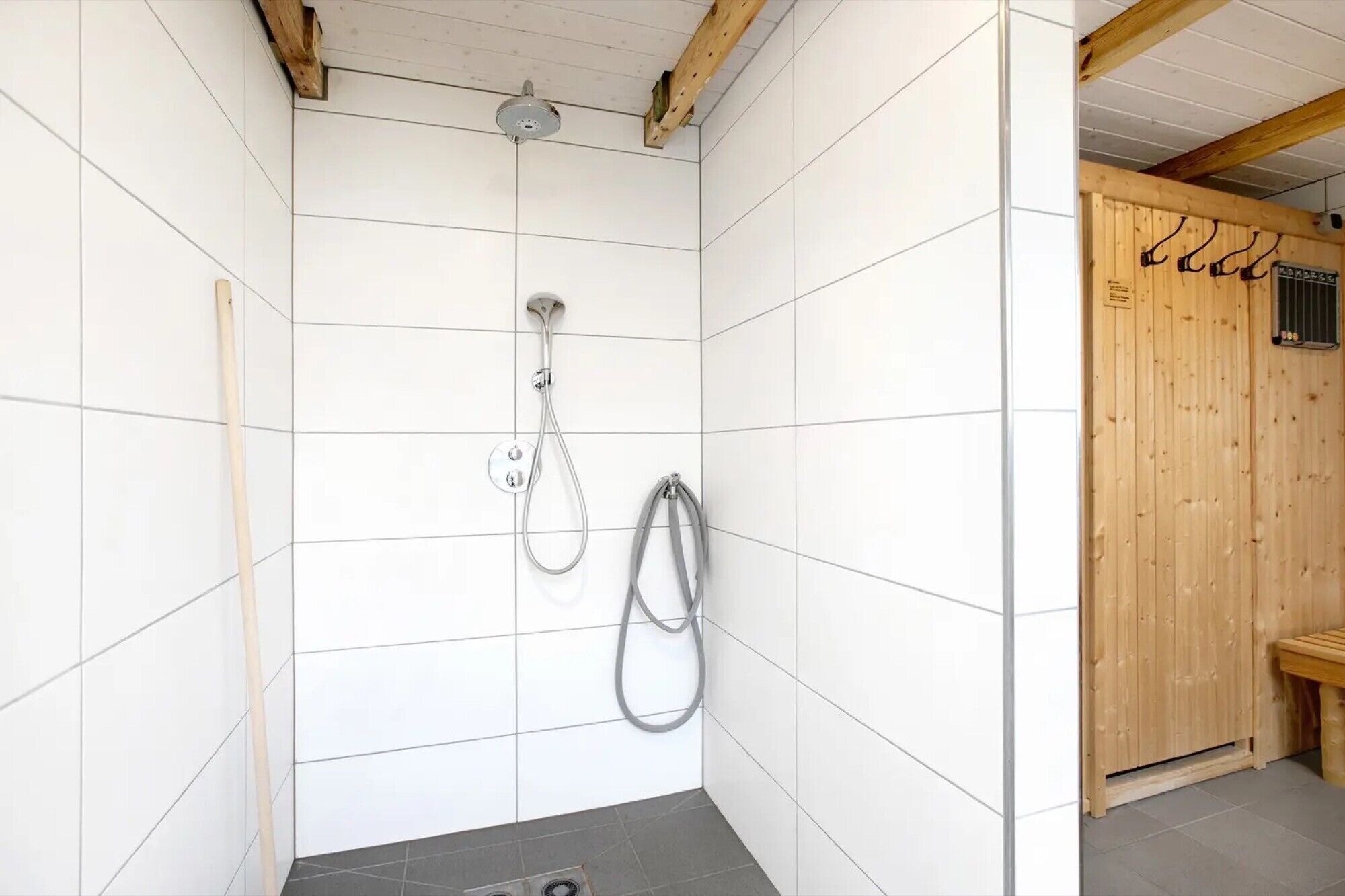 Eine Dusche mit Duschhandstück, Wandarmatur und Duschschlauch.
