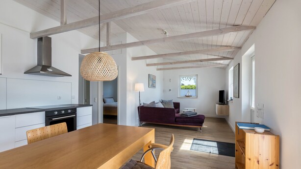 Une cuisine moderne avec une table à manger en bois, des chaises et un luminaire suspendu.