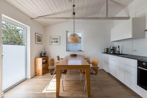 Eine moderne Küche mit Holztisch, weißen Schränken und einer Pendelleuchte.