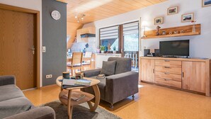 Ein Wohnzimmer mit Sofa, Couchtisch, Fernseher und Holzschrank.