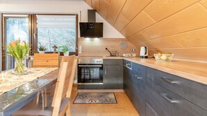 A modern kitchen with a wooden countertop, stainless steel appliances, and a view of the outdoors.