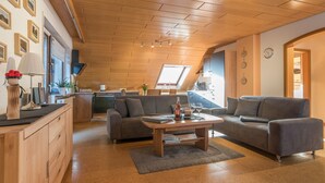 A modern living room with a sofa, coffee table, and a kitchen in the background.