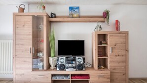 Un mobile in legno con un televisore, degli altoparlanti e cassetti contenitori.