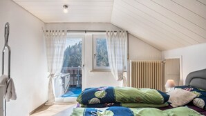 Una camera da letto con un letto, una finestra con tende, un termosifone e una porta.