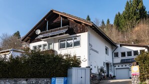 Un edificio bianco con tetto spiovente, pannelli solari e un cartello che segnala un'area parcheggio privata.