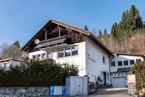 Un bâtiment blanc avec un toit en pente, des panneaux solaires et un panneau indiquant un espace de stationnement privé.
