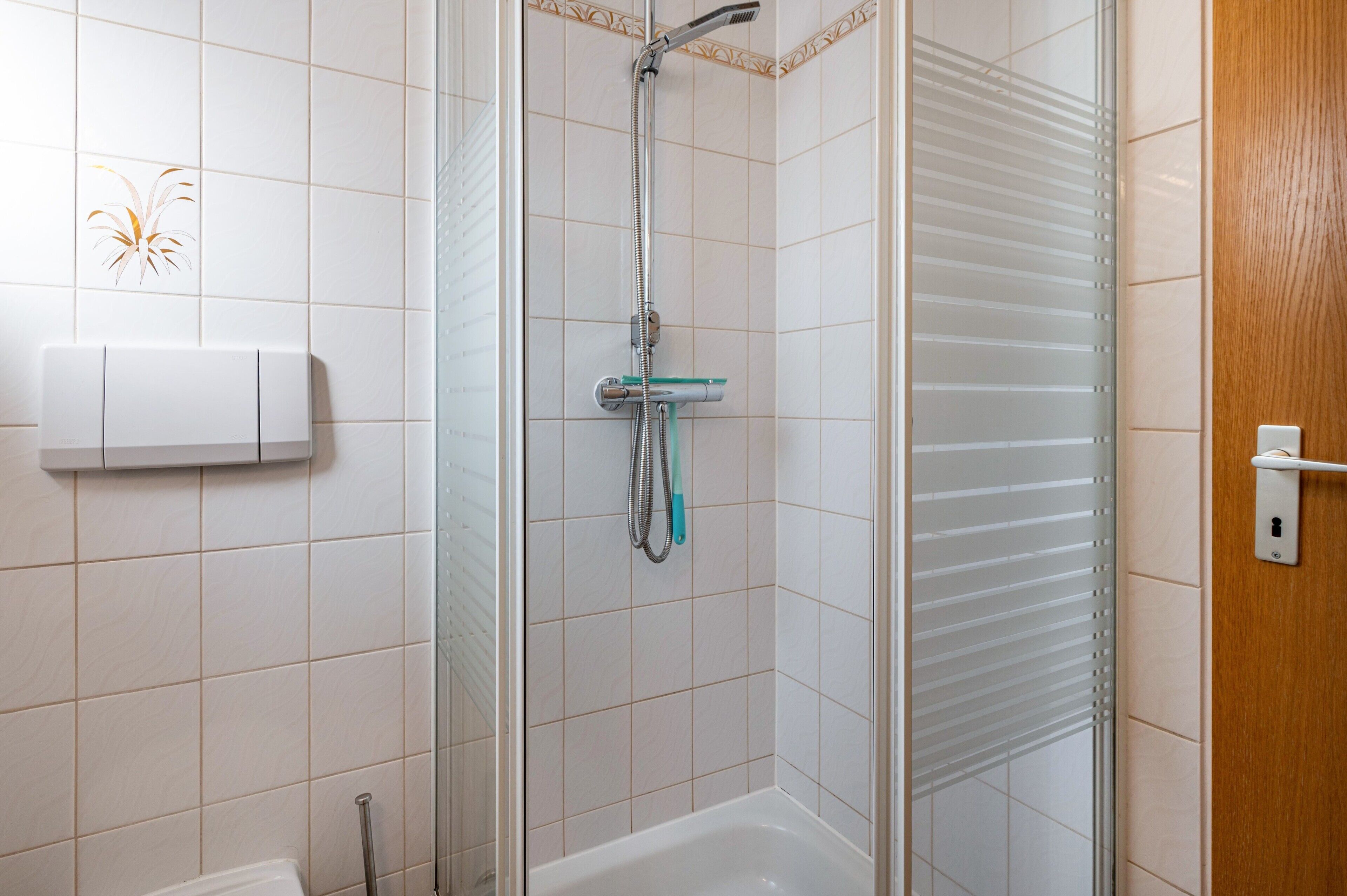 A bathroom with a shower, a toilet, and a towel rack.