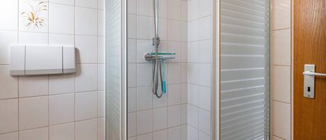 A bathroom with a shower, a toilet, and a towel rack.