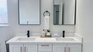 A modern bathroom with two sinks, a large mirror, and a towel ring.