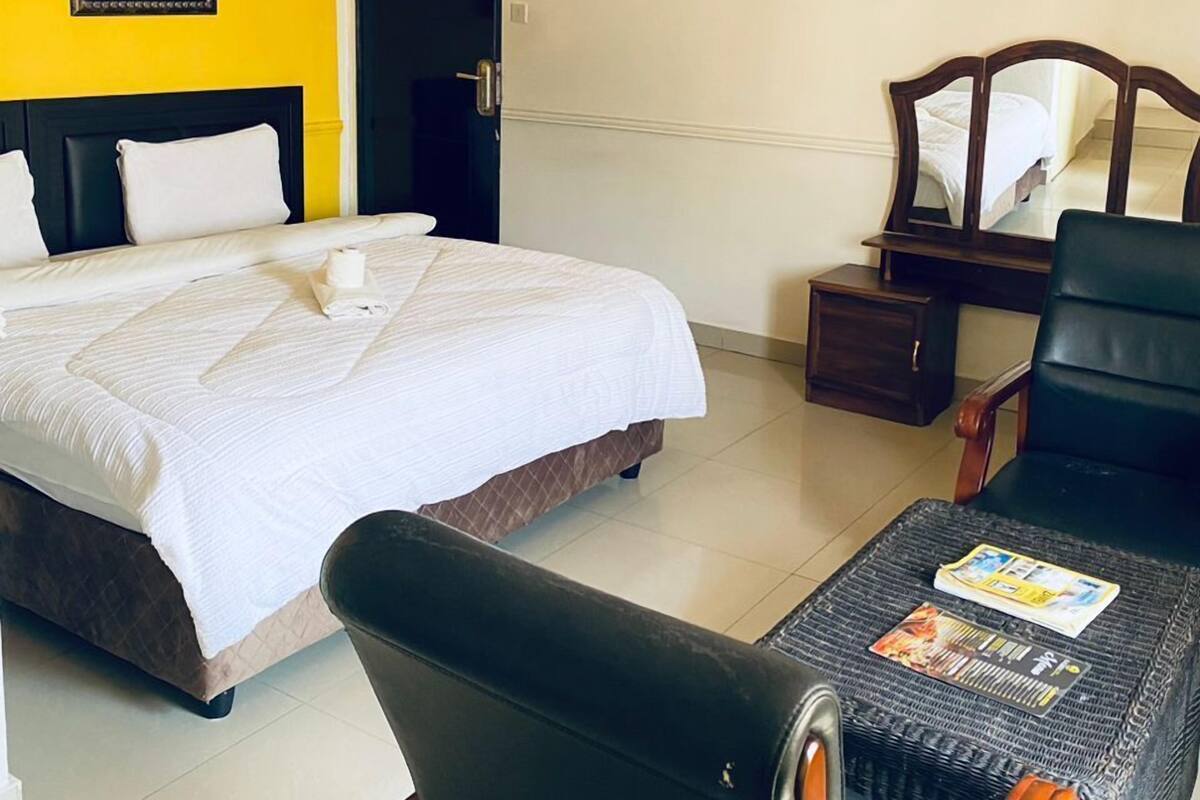 A hotel room with a bed, a desk, a chair, and a mirror.