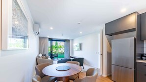 A modern kitchen with a large refrigerator, a dining table with chairs, and a view of the outdoors.