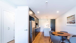 A modern kitchen with built-in appliances, a dining area with a round table and chairs, and a white door leading to another room.