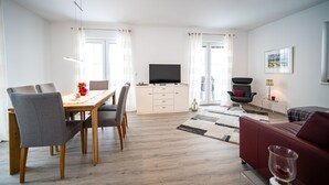 A modern living room with a dining area, a flat-screen TV, and a red sofa.