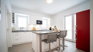 A modern kitchen with white cabinets, a central island, and two bar stools.