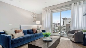 Een moderne woonkamer met een blauwe bank, een salontafel en een grijze fauteuil.