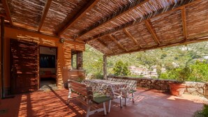 Un espacio de estar techado al aire libre con una mesa y bancos, con vistas a un paisaje pintoresco.