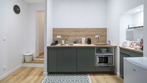 A compact kitchen with a wooden countertop, built-in appliances, and a small refrigerator.