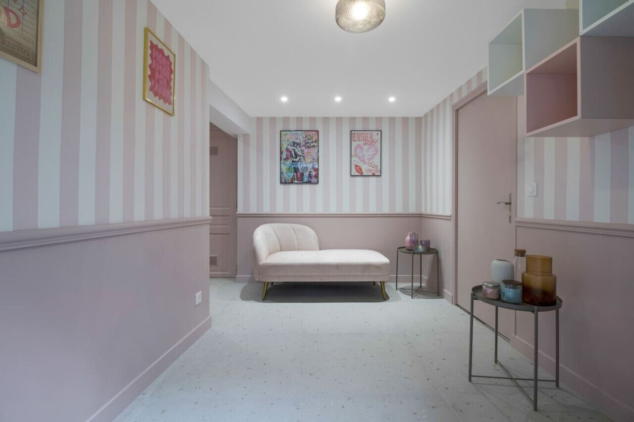 A room with a bed, striped walls, and two framed artworks.