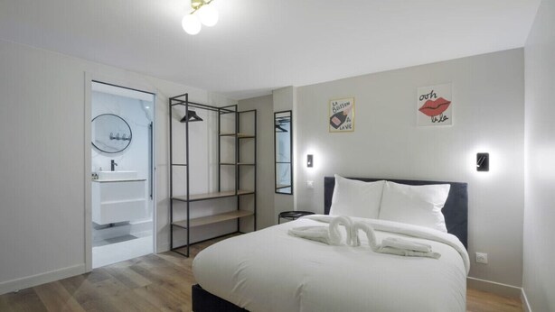 Un dormitorio moderno con una cama grande, un vestidor y un baño con puerta de vidrio.