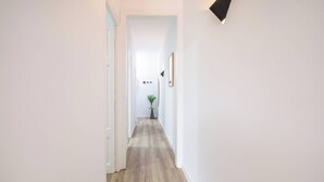 Ein Korridor mit Holzboden, weißen Wänden und einer kleinen Pflanze auf einem Tisch.